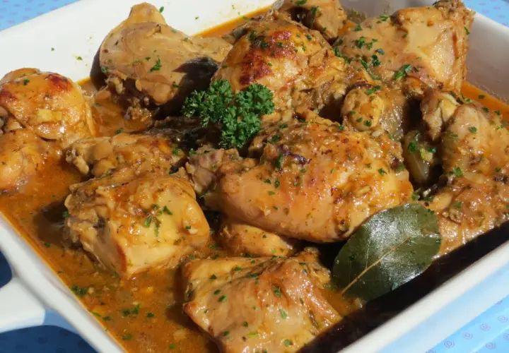 Delicioso conejo guisado en salsa dorada, con perejil picado y una hoja de laurel.
