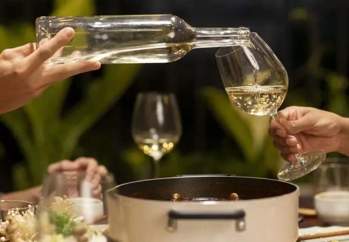 Sirviendo vino blanco fresco en copas, perfecto para acompañar una cena con amigos.