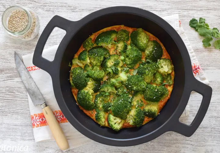 Tortilla de brócoli recién horneada, adornada con semillas de sésamo y perejil, lista para servir.