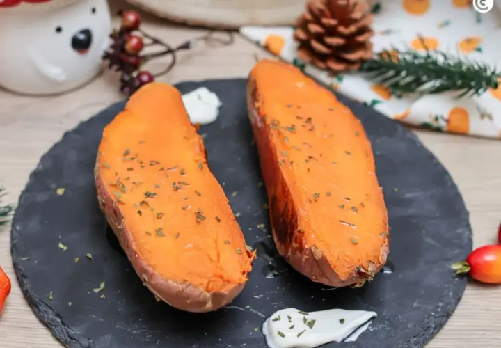 Dos mitades de boniato al horno, tiernas y doradas, espolvoreadas con hierbas, acompañadas de una cremosa salsa.