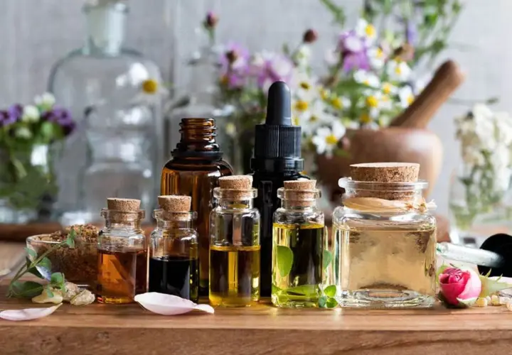 Varias botellas de aceites esenciales, algunas con hierbas y flores, sugieren el mejor aceite para la circulación.