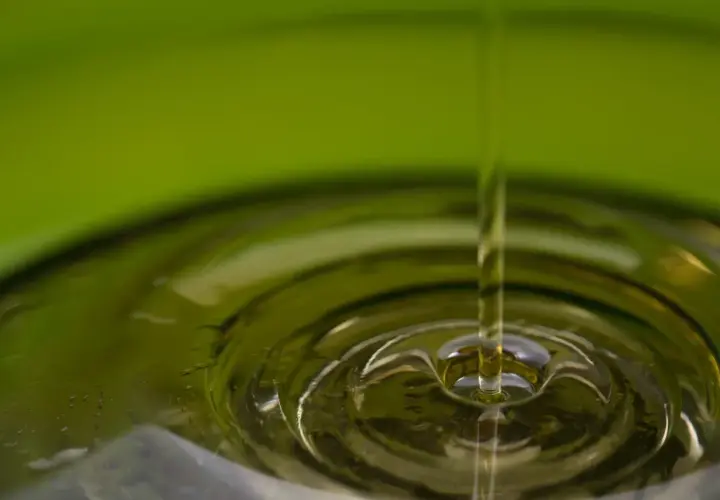 Gota de aceite cayendo en un líquido, creando ondas. El aceite de oliva refinado es malo para la salud.