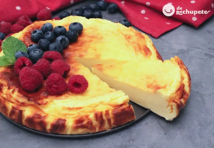 Tarta de yogur griego dorada, decorada con frambuesas y arándanos frescos. ¡Un postre irresistible!