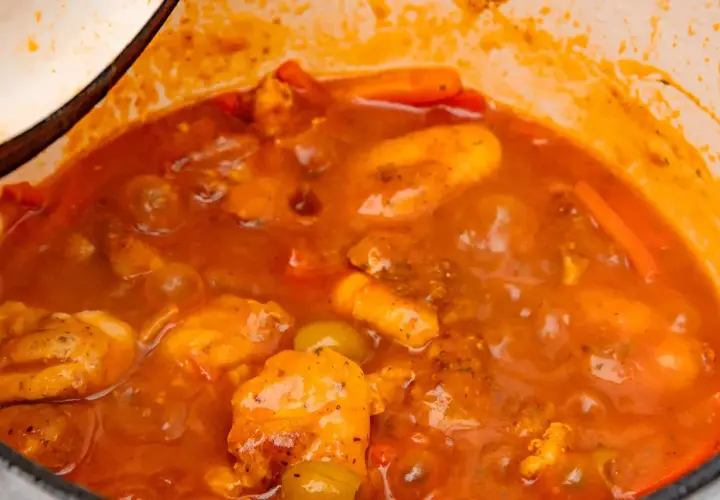 Guiso casero de pollo con tomate, zanahoria y aceitunas verdes, cocinado a fuego lento en una olla.