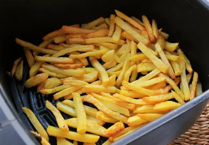 Patatas fritas doradas y crujientes listas para disfrutar, recién salidas de la freidora de aire.