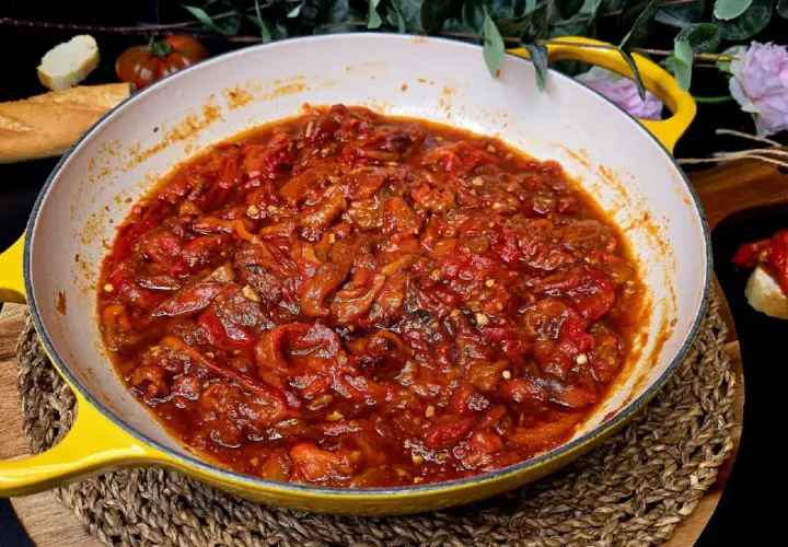 Asadillo manchego recién hecho en sartén amarilla, acompañado de pan y tomates.