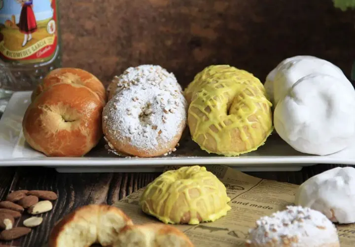 Rosquillas tontas, algunas cubiertas de azúcar glas y almendras, otras con glaseado amarillo y unas blancas. ¡Un dulce tentempié!