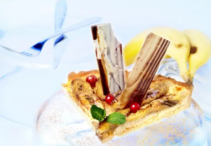 Deliciosa tarta de plátano con trozos de chocolate y frutos rojos, lista para disfrutar.