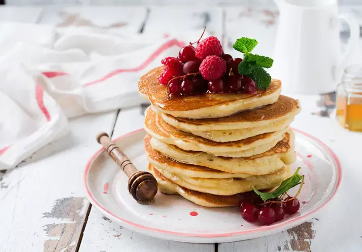 Deliciosas tortitas de avena apiladas, cubiertas con frutos rojos y menta. Un desayuno perfecto para empezar el día.
