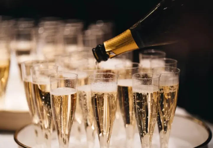 Servicio de cava más caro, burbujas doradas llenando copas para una celebración especial.