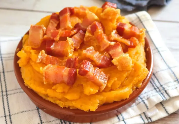 Patatas revolconas cremosas y doradas, cubiertas con trozos crujientes de panceta. Un plato tradicional español.