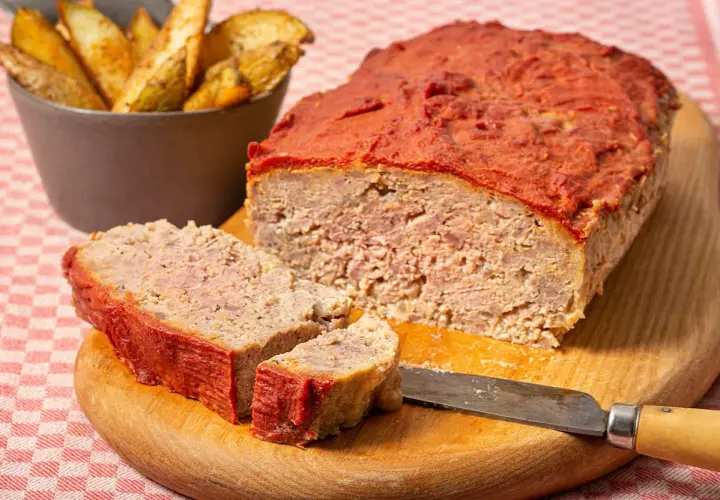 Un delicioso pastel de carne picada cubierto de salsa de tomate, servido con patatas gajo.