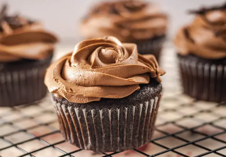 Deliciosas magdalenas sin huevo con glaseado de chocolate cremoso, dispuestas en una rejilla.