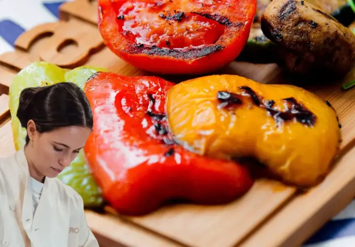 Chef preparando pimientos asados, tomates y champiñones a la parrilla en una tabla de madera.