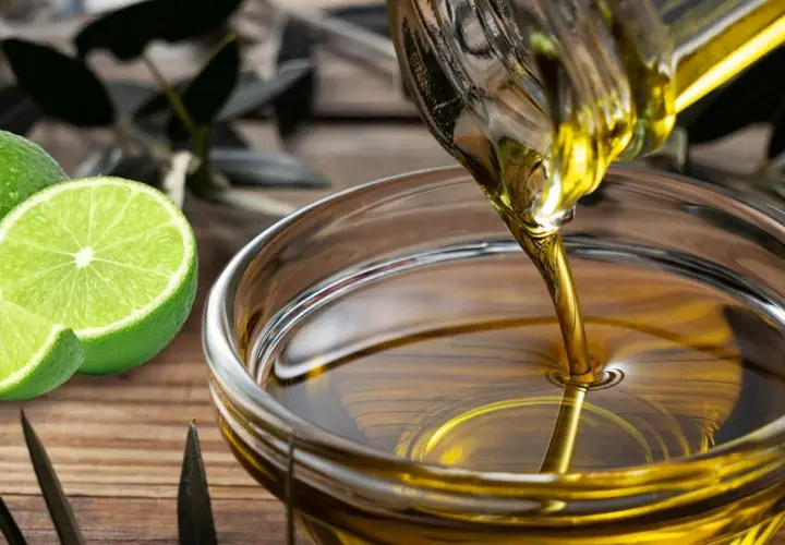 Aceite y limón en ayunas: conoce las contraindicaciones. Se ve aceite vertiéndose en un cuenco, junto a limones frescos.