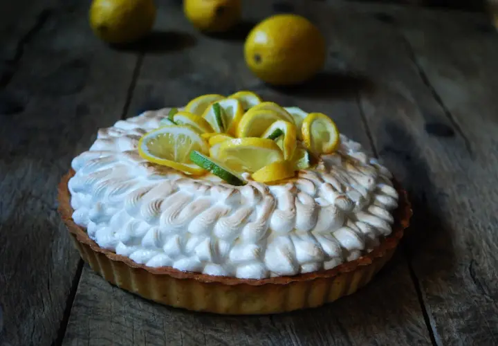 Deliciosa tarta de limón con merengue dorado y rodajas de limón fresco.