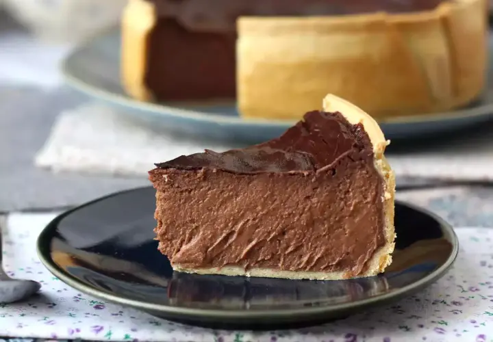 Rebanada de flan de chocolate con cobertura brillante y base dorada, servida en plato oscuro.