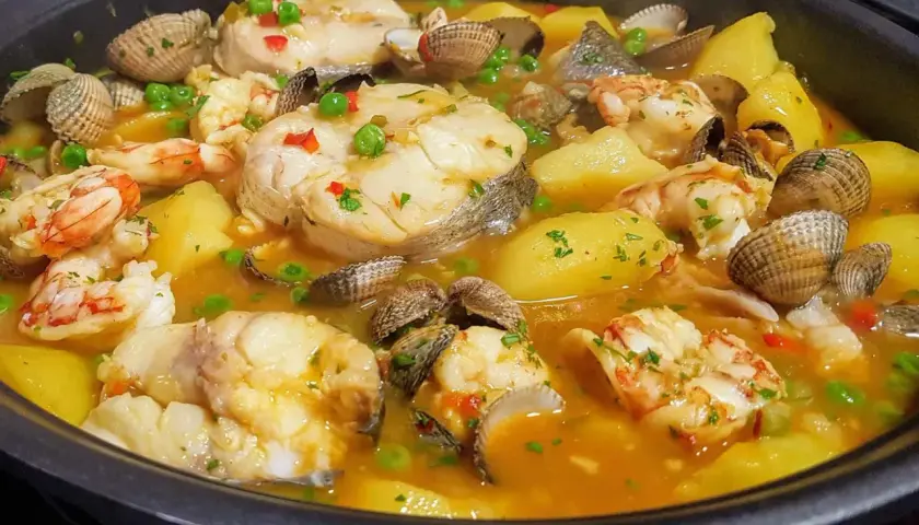 Merluza a la cazuela con patatas, gambas y berberechos, un plato marinero reconfortante y lleno de sabor.
