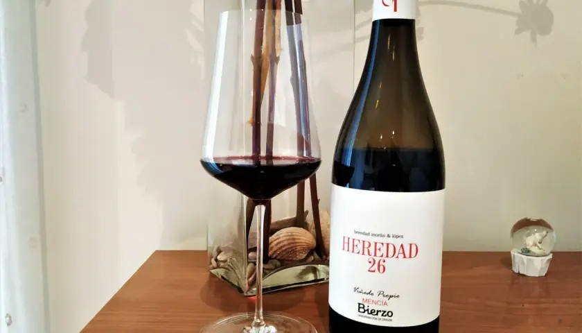 Una copa de vino tinto junto a una botella de vino del Bierzo. El corcho yace cerca, listo para otra degustación.