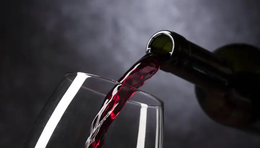 Vino tinto de Rioja o Ribera del Duero vertiéndose de una botella a una copa, creando un momento de placer.