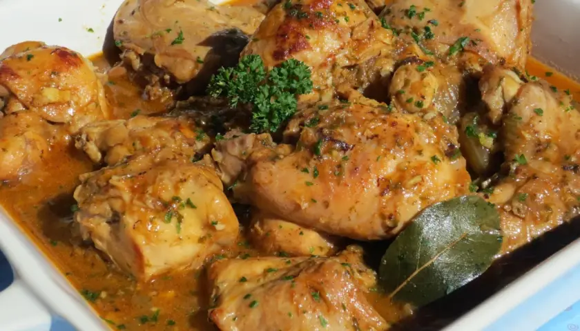 Delicioso conejo guisado en salsa dorada, con perejil picado y una hoja de laurel.