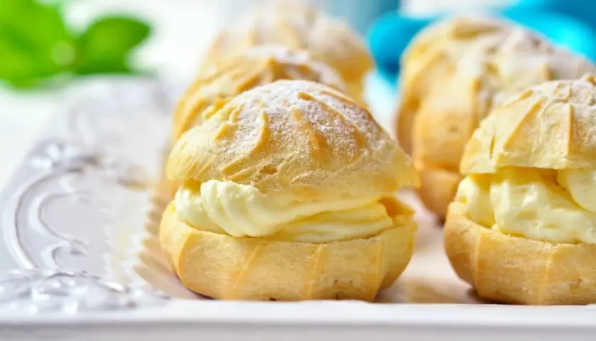 Profiteroles rellenos de crema pastelera Thermomix, espolvoreados con azúcar glas. Deliciosos y fáciles de preparar.