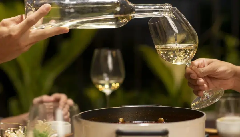 Sirviendo vino blanco fresco en copas, perfecto para acompañar una cena con amigos.