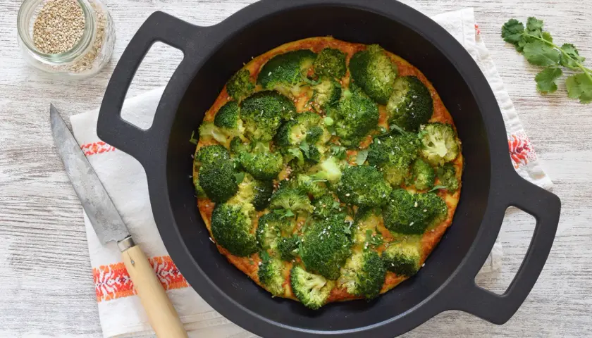 Tortilla de brócoli recién horneada, adornada con semillas de sésamo y perejil, lista para servir.