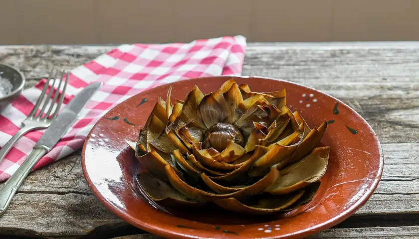 Alcachofas al horno, doradas y tiernas, listas para disfrutar en un plato rústico.