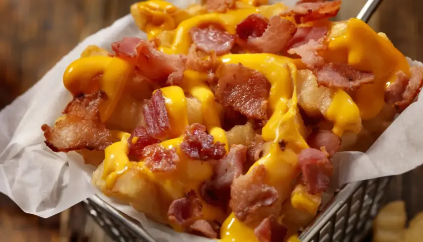 Patatas fritas crujientes cubiertas con queso fundido y trozos de bacon ahumado. ¡Un placer irresistible!