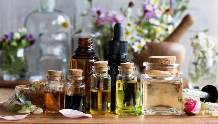 Varias botellas de aceites esenciales, algunas con hierbas y flores, sugieren el mejor aceite para la circulación.