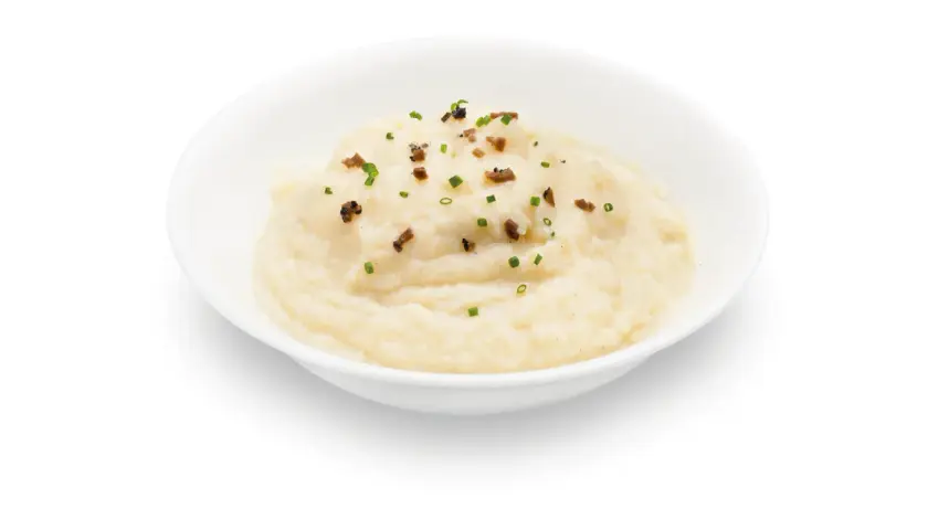 Un cremoso parmentier de patata, adornado con trocitos de bacon crujiente y cebollino fresco.