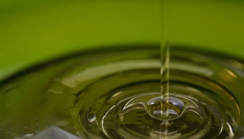 Gota de aceite cayendo en un líquido, creando ondas. El aceite de oliva refinado es malo para la salud.