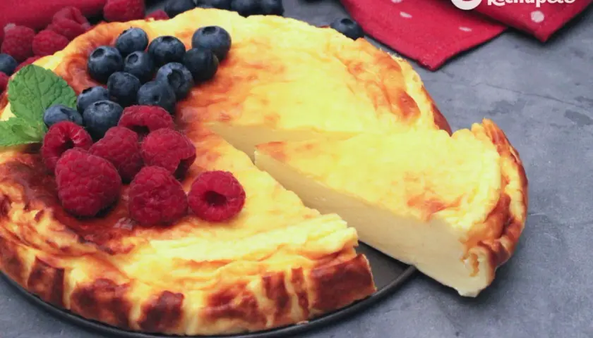 Tarta de yogur griego dorada, decorada con frambuesas y arándanos frescos. ¡Un postre irresistible!