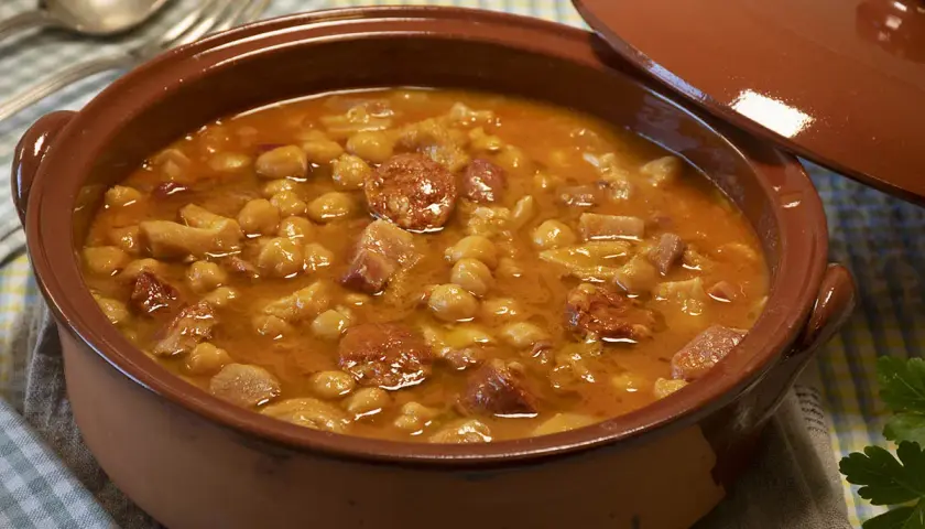Un plato humeante de callos a la gallega, con garbanzos, chorizo y trozos de carne en una cazuela de barro.