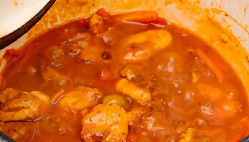 Guiso casero de pollo con tomate, zanahoria y aceitunas verdes, cocinado a fuego lento en una olla.