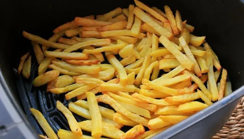 Patatas fritas doradas y crujientes listas para disfrutar, recién salidas de la freidora de aire.