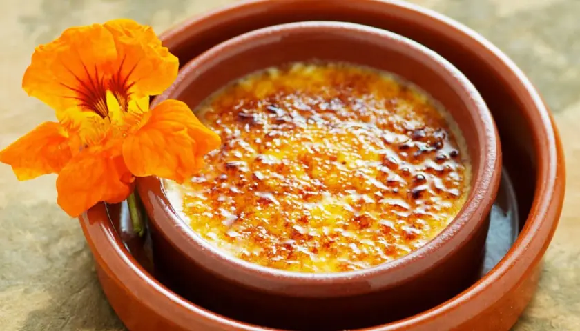 Crema catalana con una flor naranja. Una delicia para tu crema catalana receta.