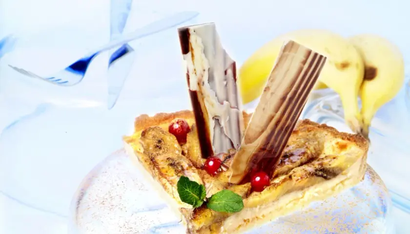 Deliciosa tarta de plátano con trozos de chocolate y frutos rojos, lista para disfrutar.