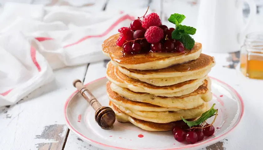 Deliciosas tortitas de avena apiladas, cubiertas con frutos rojos y menta. Un desayuno perfecto para empezar el día.