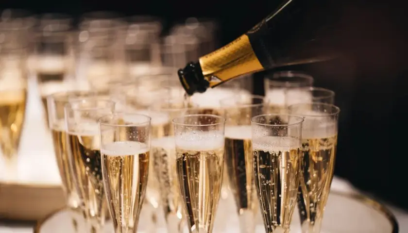 Servicio de cava más caro, burbujas doradas llenando copas para una celebración especial.