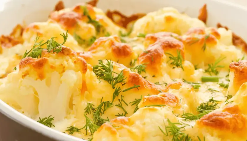 Coliflor al horno gratinada con queso y hierbas frescas, un plato reconfortante y delicioso.