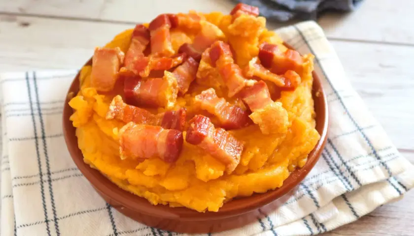 Patatas revolconas cremosas y doradas, cubiertas con trozos crujientes de panceta. Un plato tradicional español.