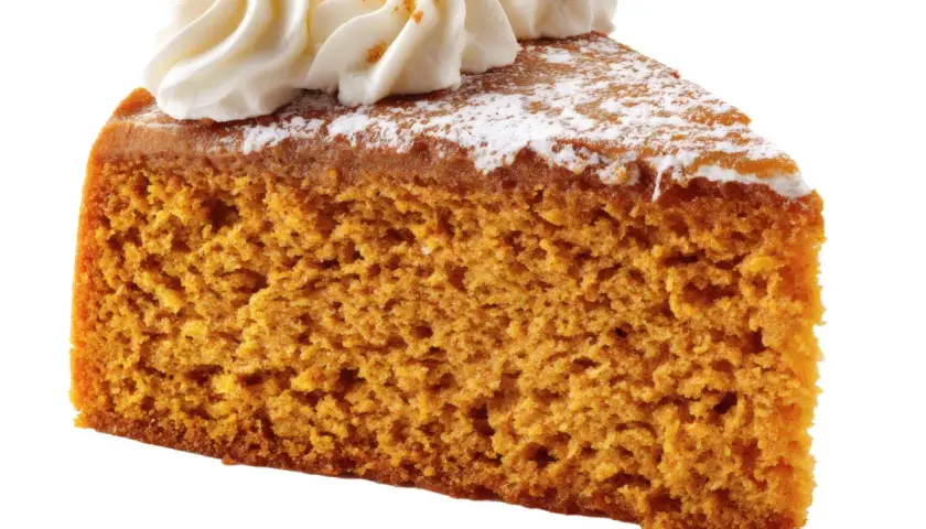 Rebanada de bizcocho de calabaza esponjoso, cubierto con crema batida y espolvoreado con azúcar glas.