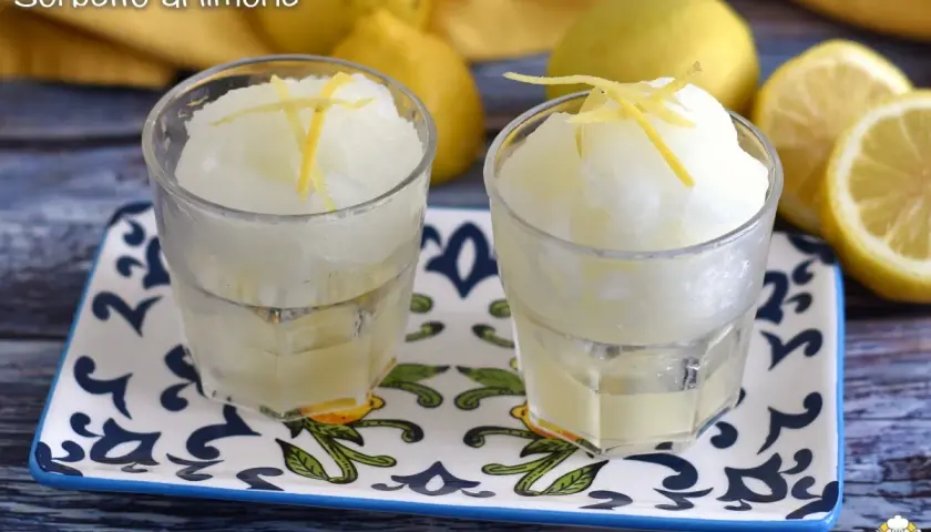Dos vasos de sorbete de limón, refrescante y con ralladura de limón encima.