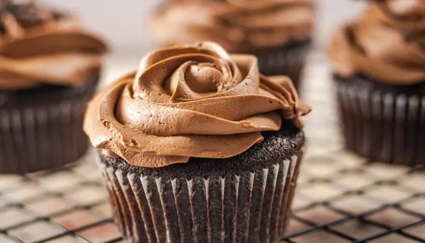 Deliciosas magdalenas sin huevo con glaseado de chocolate cremoso, dispuestas en una rejilla.
