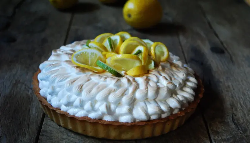 Deliciosa tarta de limón con merengue dorado y rodajas de limón fresco.