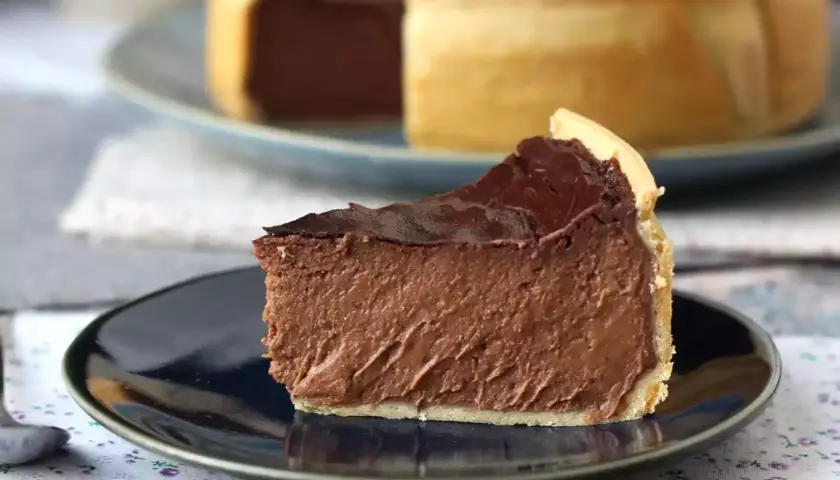 Rebanada de flan de chocolate con cobertura brillante y base dorada, servida en plato oscuro.