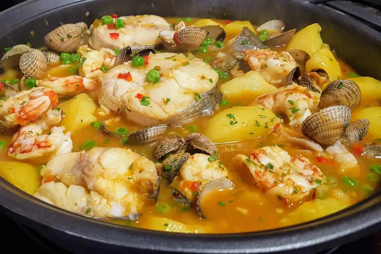 Merluza a la cazuela con patatas, gambas y berberechos, un plato marinero reconfortante y lleno de sabor.