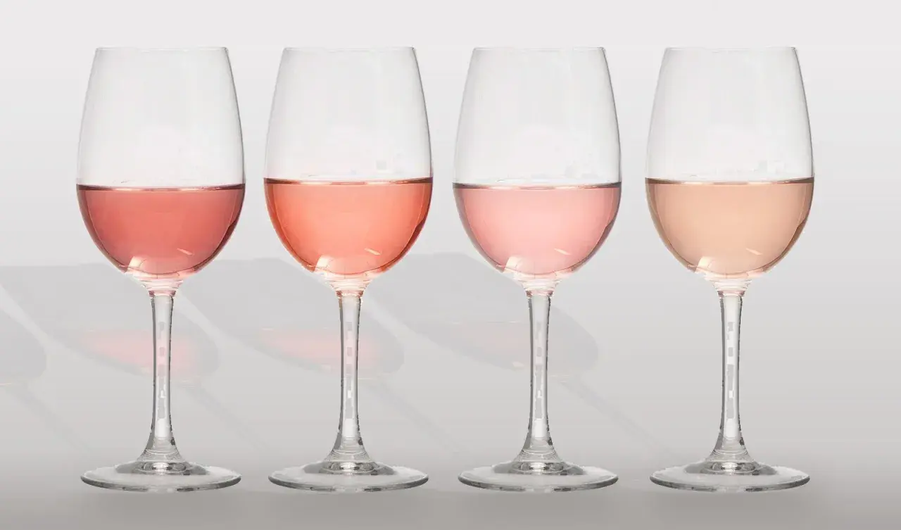 Cuatro copas de vino con diferentes tonos de clarete o rosado, desde un rosa intenso hasta un salmón pálido.